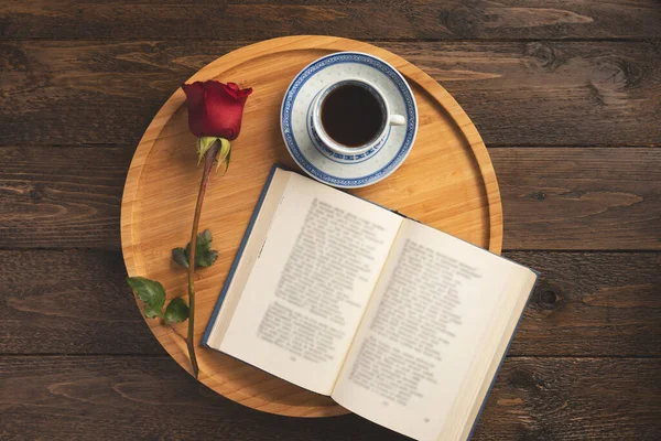 Romantik kahvaltı. Ahşap tepside kitap, gül, bir fincan kahve, ahşap arka planda. Düz konum, üst görünüm, kopyalama alanı.