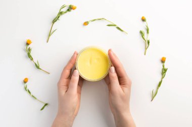 Organik kozmetik konsepti. Beyaz arka planda izole edilmiş kadın elleri ve kozmetik kremi. Düz konum, üst görünüm, kopyalama alanı.