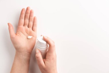 Bakım kozmetik konsepti. Beyaz arka planda izole edilmiş kozmetik krem konteynırı tutan bir kadın. Düz konum, üst görünüm, kopyalama alanı.