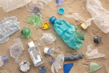 Ekolojik felaket, dünya okyanusunun kirliliği. Kullanılmış plastik, kumun üstüne dökülmüş, üst manzara.