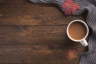 Beyaz örgü eşarplı düz bir bez, bir fincan kahve, ahşap masa üzerinde. Hygge tarzı, sıcak sonbahar ya da kış tatili konsepti. Düz yatıyordu, üstten, yukarıdan..