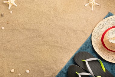 Güzel yaz tatili plaj arka planında hasır şapka ve parmak arası terliklerle kumlu arka plan, sınır tasarımı, fotokopi alanı ile üstten manzara