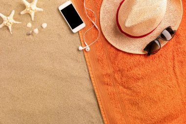 Üst görünüm hasır şapka ve fotokopi alanı olan akıllı telefon. Kumda gezgin aksesuarları. Seyahat tatili konsepti. Yaz dönemi. Havludan yapılmış kenar bileşimi