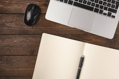 Not defteri, dizüstü bilgisayar ve ahşap masada fare olan ofis eşyaları. Düz atış, ev konseptinde çalışmak.