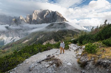 Sırt çantalı gezgin genç kadın dağın tepesine çıkıyor. Keşif Seyahat Hedefi Konsepti