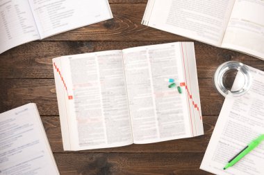 İş stresi konsepti. Çalışma masasında ilaç, kitap, kalem, kağıt ve bir bardak su ile ahşap zemin üzerinde fotokopi alanı