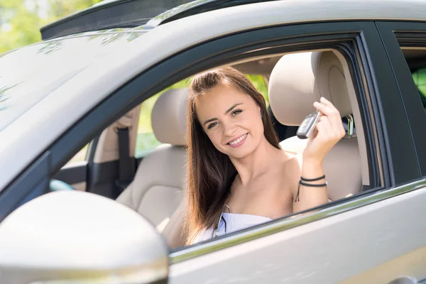 若い美しい女性はディーラーから新しい車への鍵を受け取ります — ストック写真