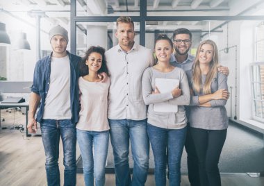 Portrait of successful creative business team standing together and laughing at camera.
