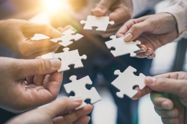 A group of business people assembling jigsaw puzzle. The concept of cooperation, teamwork, help and support in business.