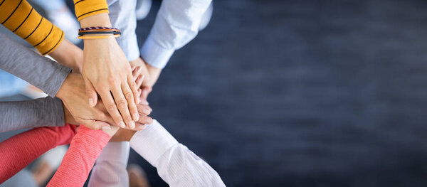 Close up top view of young business people putting their hands together. Stack of hands. Unity and teamwork concept.