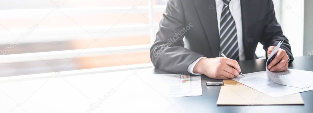 Business man signing contract document on office desk, making a deal.