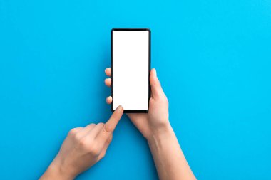 Mavi arka planda el ele tutuşan siyah telefon ve içerideki kesme yolu izole edildi. Smartphone konsepti.