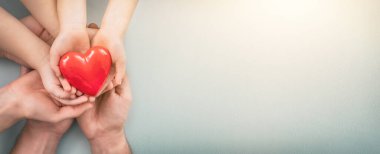 Yetişkin, anne, baba ve çocuk ellerinde kırmızı bir kalp tutuyor. Yardım, sağlık sigortası, aşk, uluslararası kardiyoloji günü kavramı.