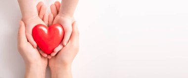 Yetişkin, anne, baba ve çocuk ellerinde kırmızı bir kalp tutuyor. Yardım, sağlık sigortası, aşk, uluslararası kardiyoloji günü kavramı.