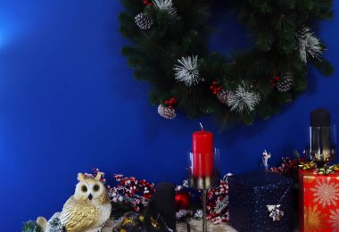 Ökseotu çelengi, mumlar ve mavi arka planda hediyeler ile Noel süslemesi.