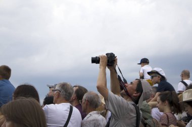 Saint-Petersburg, Rusya, 28 Temmuz 2019. Donanma Günü 'nde fotoğraf makinesi olan bir adam insanların kafalarının üstünde performans sergiliyor.