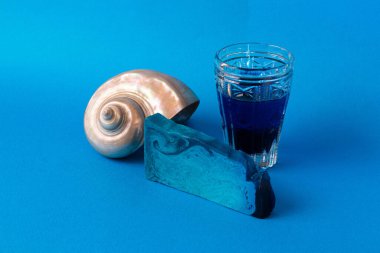 Mavi nane aromalı el yapımı sabun, inci kabuğu ve mavi sıvılı cam ile durgun bir hayat.