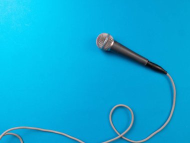 Turkuaz arka planda uzun gri kabloyla dinamik mikrofon, profesyonel ekipman