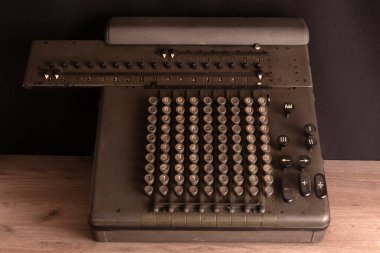 Eski sayma mekanizması, tozlu vintage aritmometre siyah kumaşa karşı tahta bir tahtanın üzerinde duruyor.