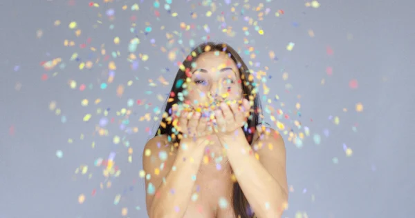 Young woman blowing colorful New Year confetti — Stock Photo, Image