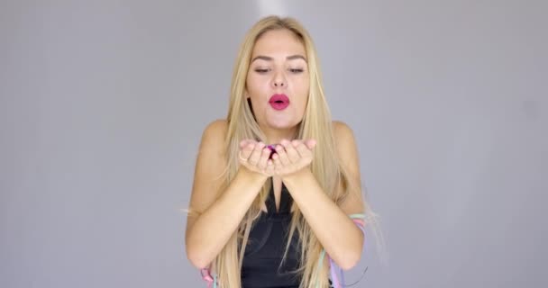 Sexy, blond dziewczyna dmuchanie konfetti do kierunku aparatu — Wideo stockowe