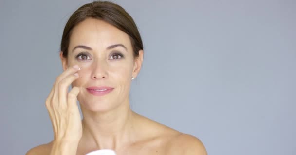 Hermosa mujer joven aplicando crema facial — Vídeo de stock