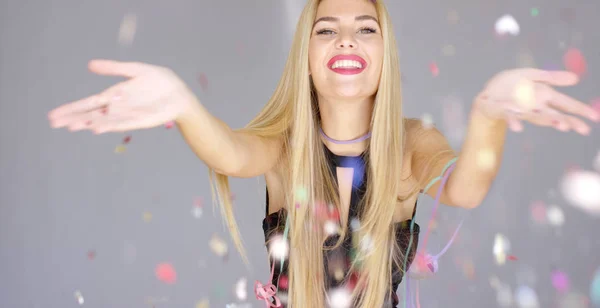 Sexy, blonďatá dívka foukání konfety do směru kamery — Stock fotografie