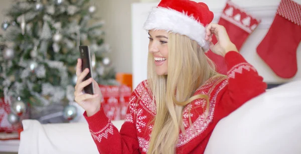 Joven chica rubia feliz en traje de Navidad usando el teléfono móvil —  Fotos de Stock