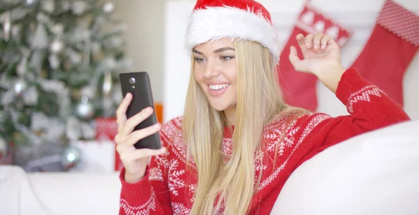 Joven chica rubia feliz en traje de Navidad usando el teléfono móvil —  Fotos de Stock