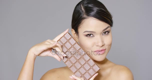 Mujer bonita mordiendo una barra de chocolate — Vídeos de Stock