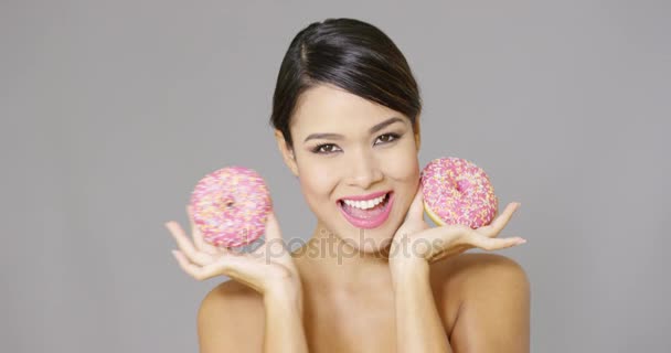 Feliz mulher vivaz segurando dois donuts rosa — Vídeo de Stock