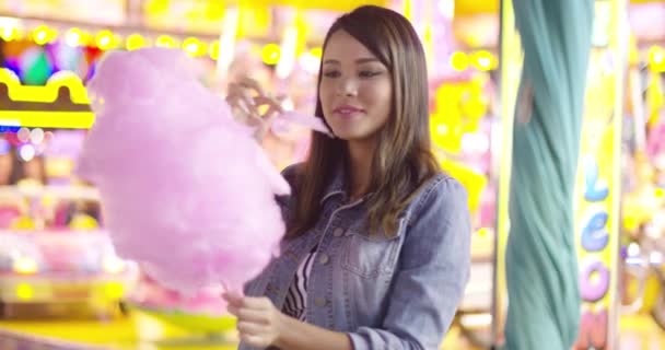 Jonge vrouw genieten van een hapje van candy floss — Stockvideo