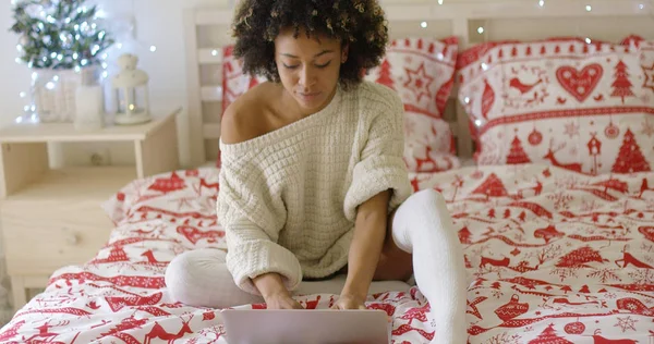 Mujer en suéter de gran tamaño en la cama usando el ordenador portátil —  Fotos de Stock