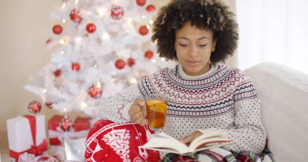 Mujer leyendo un libro delante del árbol de Navidad — Foto de Stock