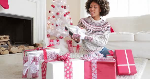 Mujer joven sonriente abriendo sus regalos en Navidad — Vídeos de Stock
