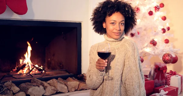 Mooie vrouw houdt wijnglas naast de open haard — Stockfoto