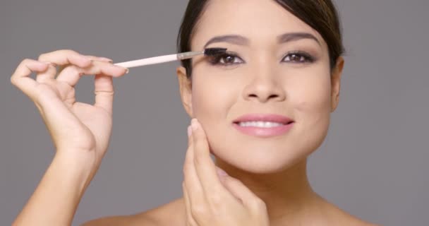 Young woman applying mascara to her eyelashes — Stock Video