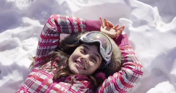 Jonge vrouw liggend op sneeuw met ski goggles — Stockvideo