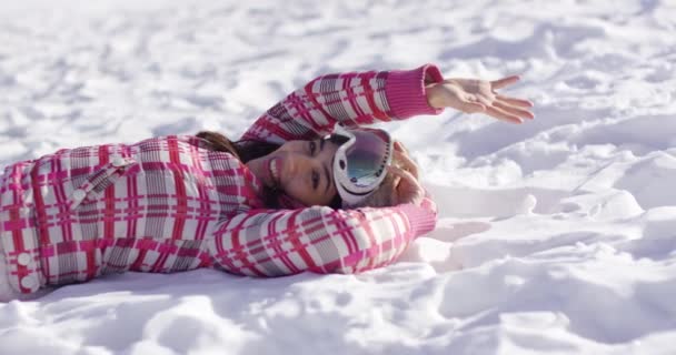 Mujer joven acostada en la nieve con gafas de esquí — Vídeos de Stock