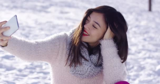 Όμορφη γυναίκα και κάθισε στο χιόνι λήψη selfie — Αρχείο Βίντεο