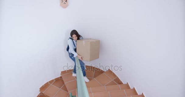 Ευτυχισμένος νεαρή γυναίκα που μεταφέρουν ένα κουτί στον επάνω όροφο — Αρχείο Βίντεο