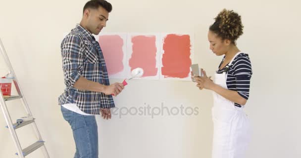 Смеющаяся молодая пара выбирает цвет краски — стоковое видео