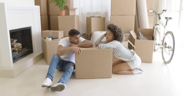 Уставшая молодая пара отдыхает на картонных коробках — стоковое видео