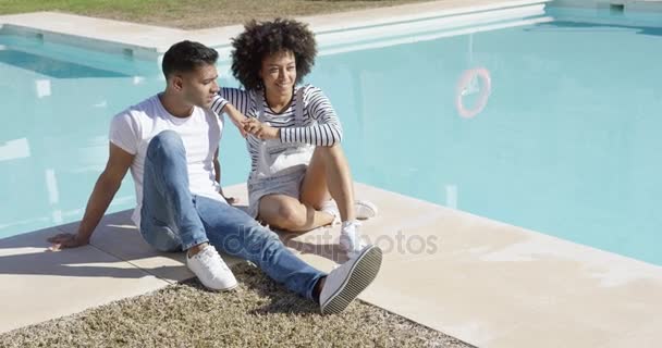 Молода жінка розслабляється зі своїм хлопцем біля басейну — стокове відео