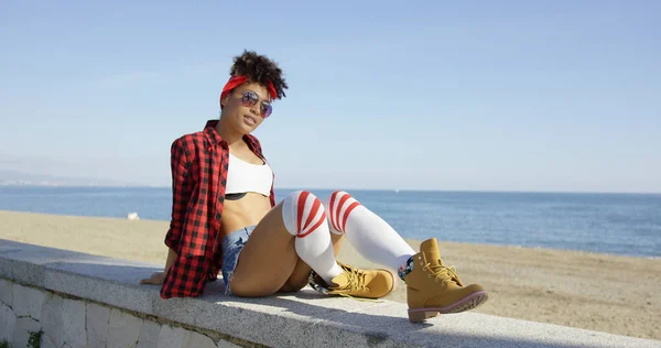 Jovem na moda relaxando em uma parede à beira-mar — Fotografia de Stock