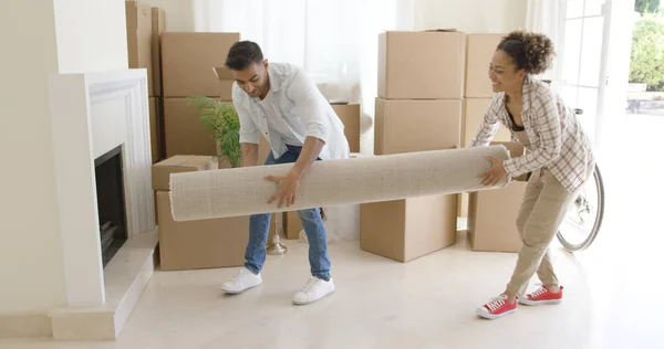 Pareja joven llevando una alfombra enrollada en una casa —  Fotos de Stock