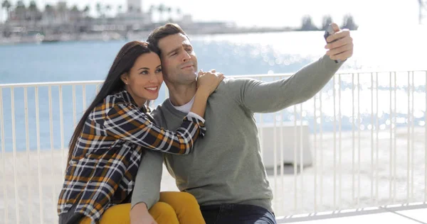 Jovem casal tirando uma selfie à beira-mar — Fotografia de Stock