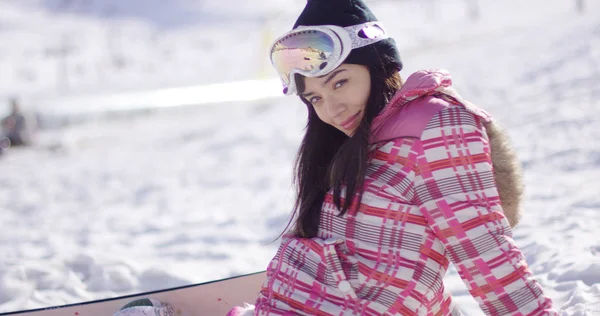 Красивая азиатская сноубордистка, сидящая на снегу — стоковое фото