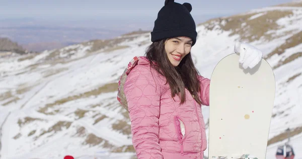 Leende kvinna med snowboard i bergen — Stockfoto