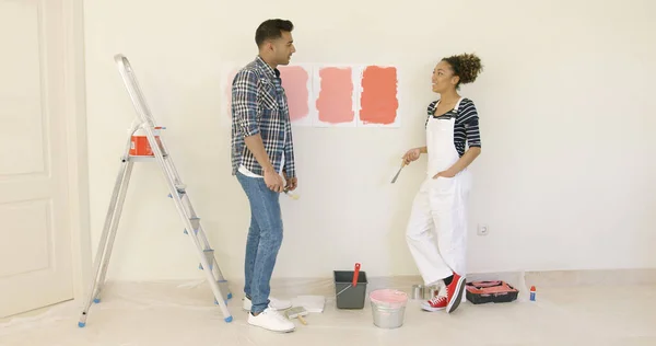 Mladý pár se snaží rozhodnout o nátěr barvy — Stock fotografie